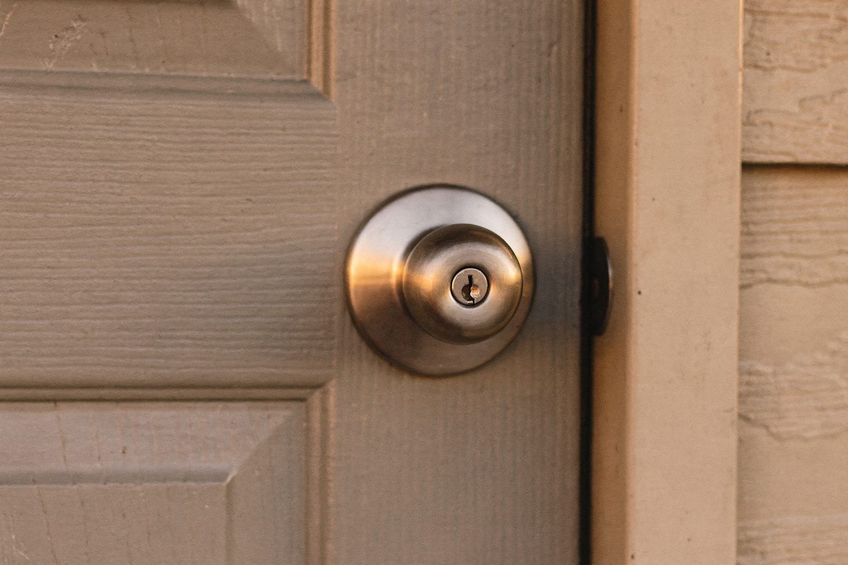A brushed-nickel deadbolt and knob set installed on a painted front door